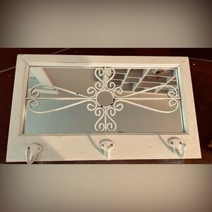 White distressed mirror with three hooks.